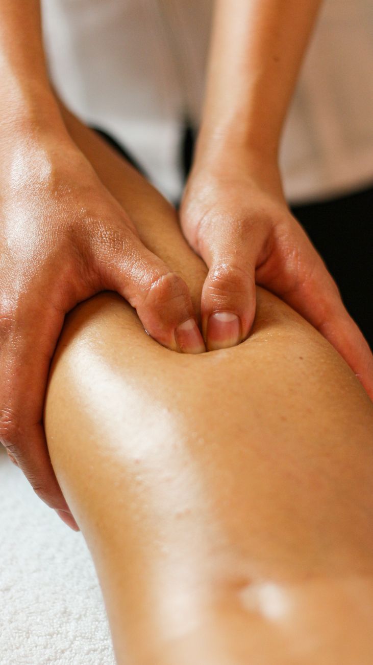 Close-up of a therapist's hands working gently along a leg during a lymphatic drainage session
