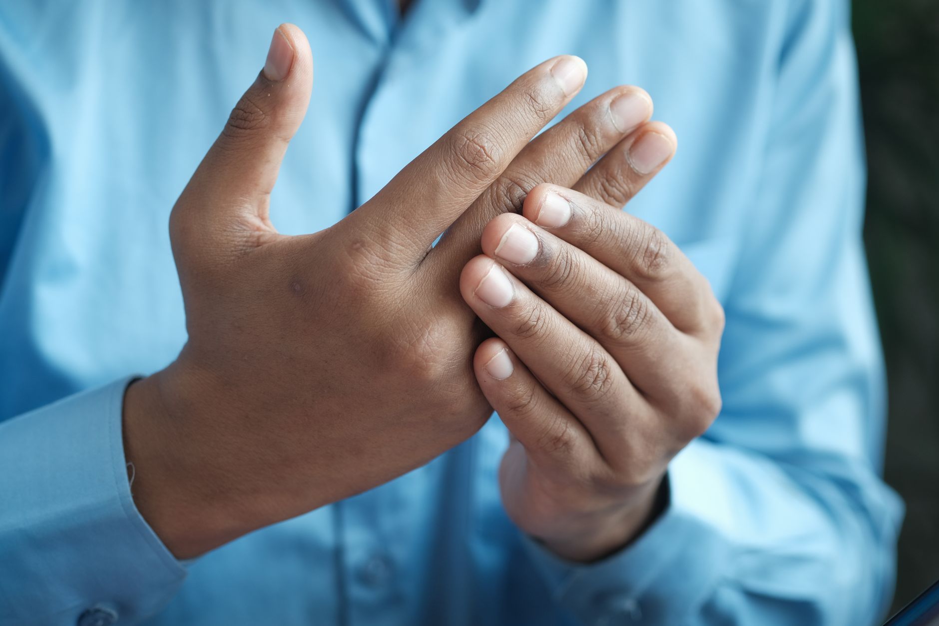A man gently holding the fingers of one hand with the other, the way people do when the hand feels numb