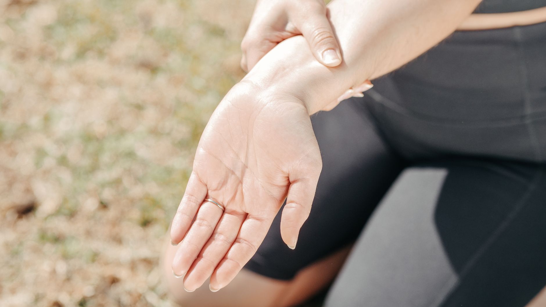 A person holding their wrist with the opposite hand, palm turned upward