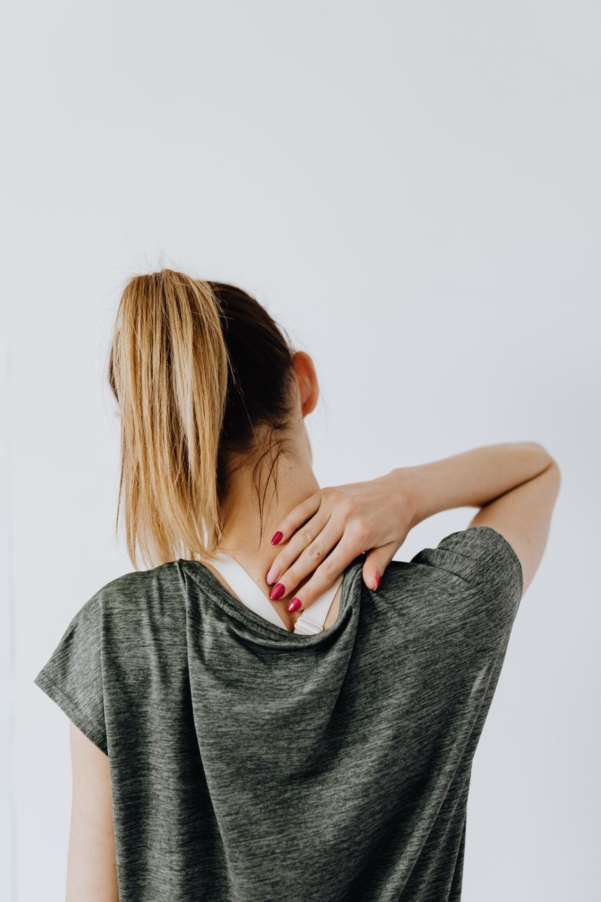 A physiotherapist standing behind a seated patient, both hands placed on the sides of his neck during an assessment