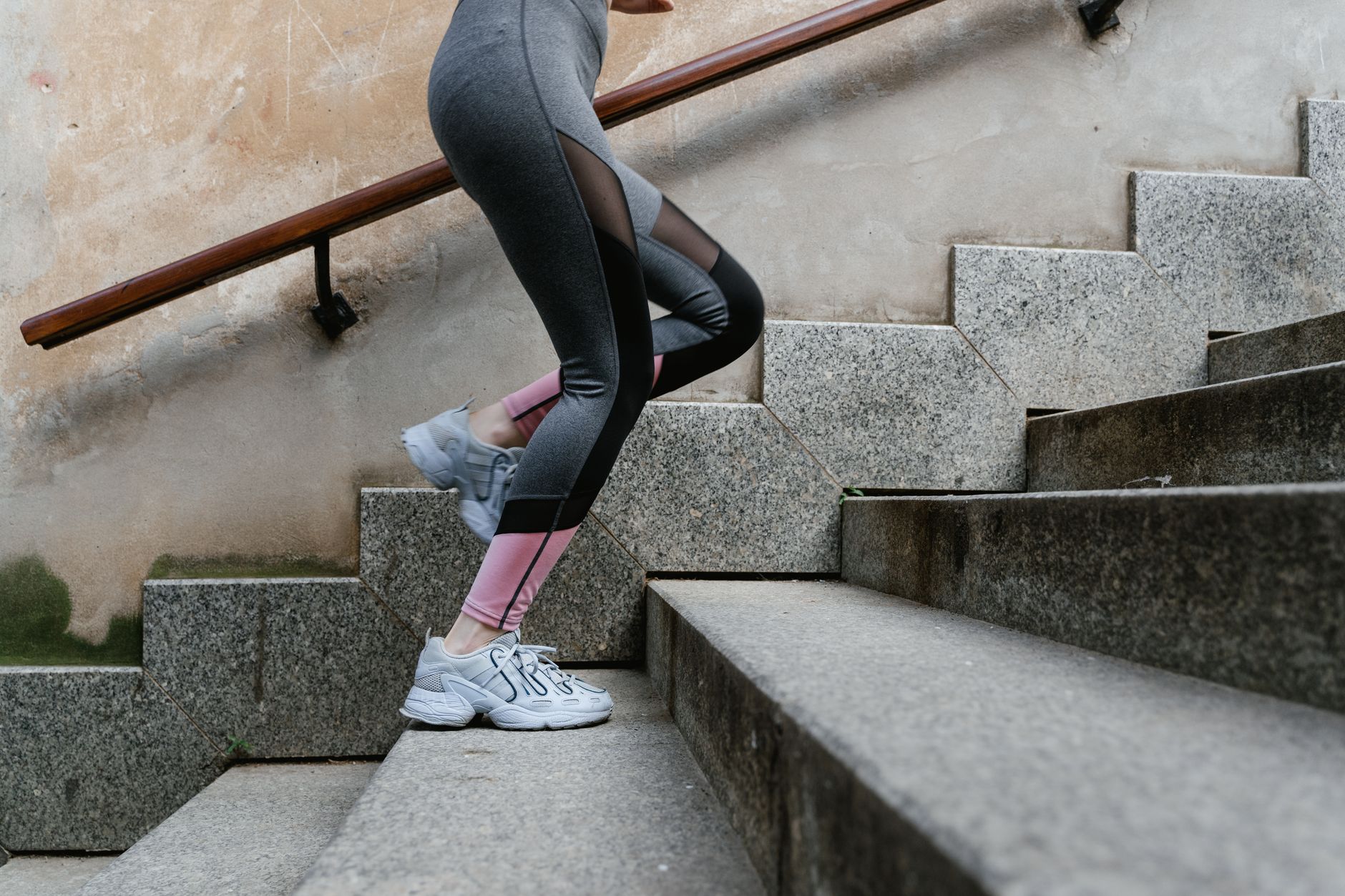 A woman's legs climbing a set of concrete outdoor stairs