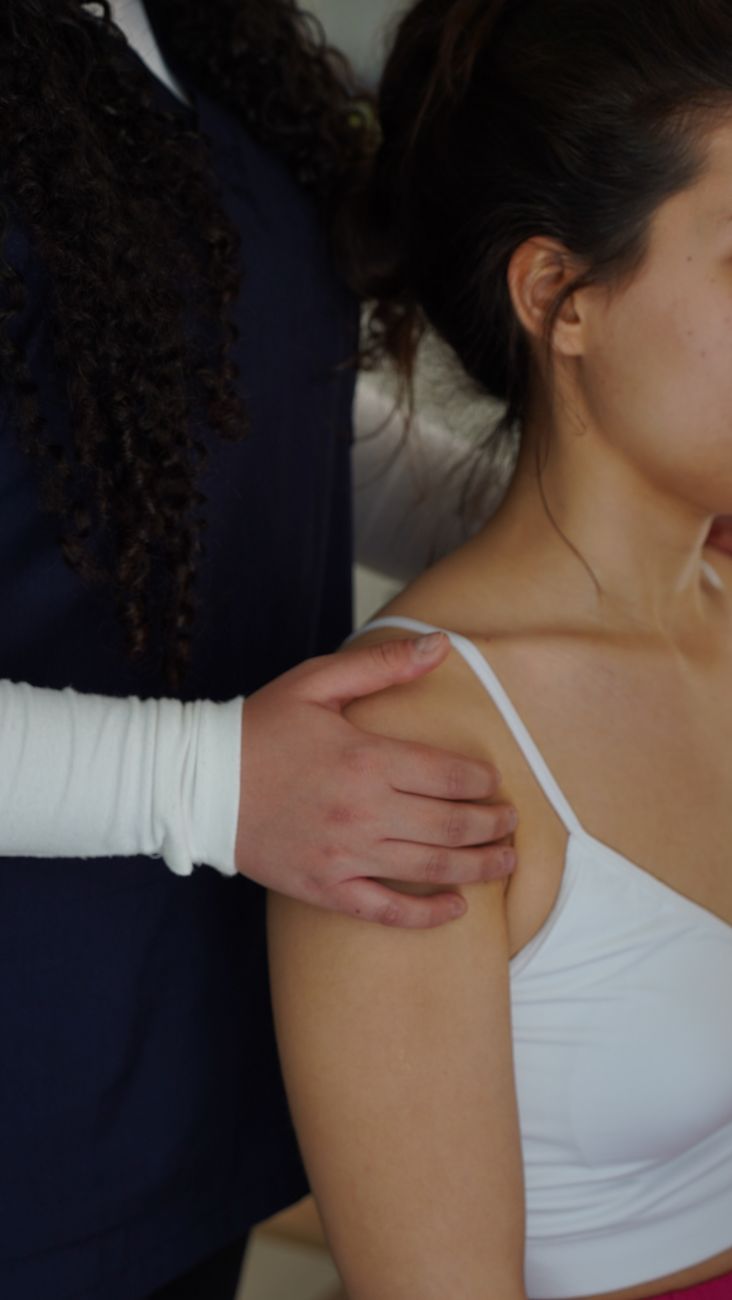 La main d'une physiothérapeute posée sur l'épaule d'une femme pendant une évaluation